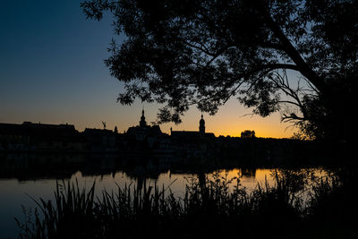 Silhouette trees by lake against sky during sunset