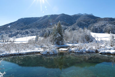 Scenic view of lake by snowcapped mountains against sky