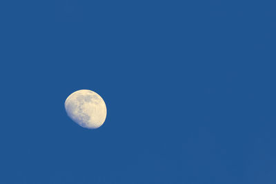 Low angle view of moon against clear blue sky