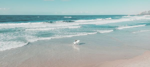 Woman with surfboard walking on beach