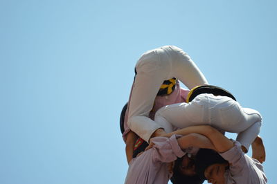 Low angle view of women against clear blue sky