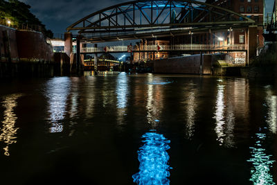 Illuminated bridge over river at night