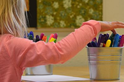 Side view of girl drawing on table at home