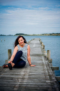 View of woman sitting on wooden pier