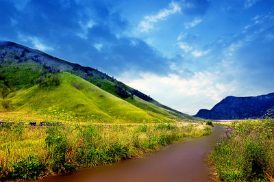 Scenic view of road amidst mountains against sky