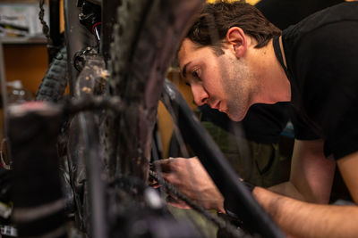 Technician with dirty hands fixing bicycle wheel while working in workshop