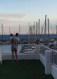 Rear view of man standing on sea shore against sky