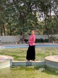 Woman standing by swimming pool against trees