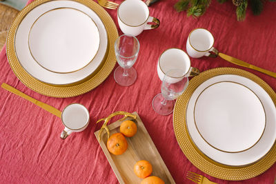 White plates with gold rims, champagne glasses, tangerines in the serving of  dinner for christmas