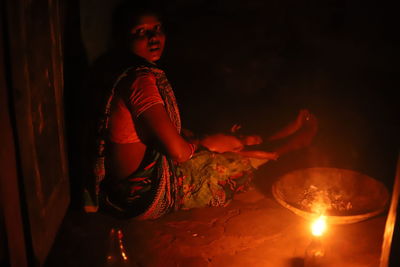 Full length of boy sitting on illuminated candle
