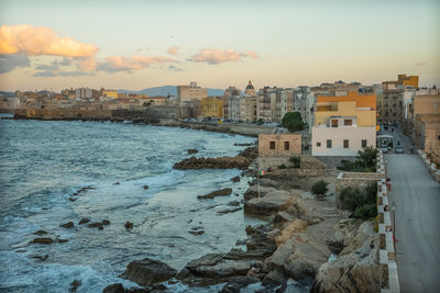 Aerial view of city by sea against sky