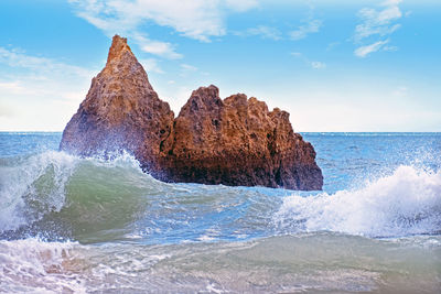 Rock formation in sea against sky