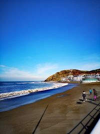 People on beach against blue sky