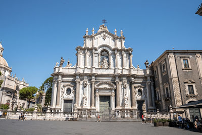 Facade of catania cathedral in city with blue sky in background during summer