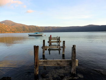 Wooden broken pier in lake against sky