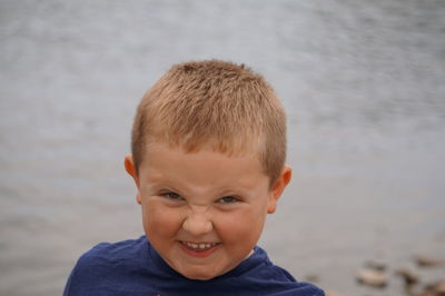 Portrait of smiling boy making a face against lake