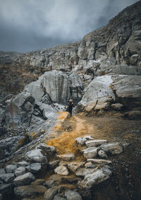 Rear view of person on rock against sky