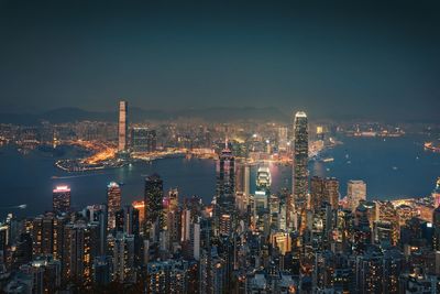 Aerial view of illuminated cityscape by river against sky at night