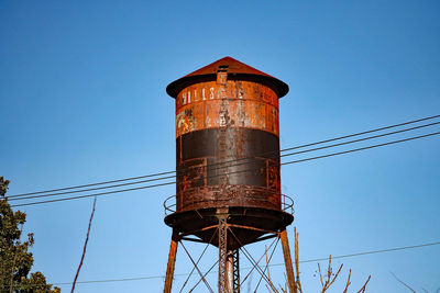 Low angle view of rusty water tower against clear sky