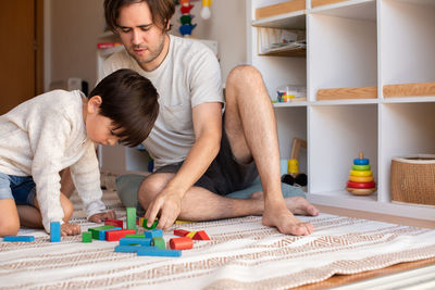 Son playing with puzzle while sitting with father at home