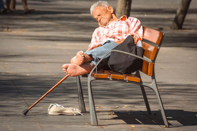 Senior man sleeping on bench at park