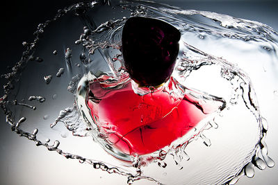 Close-up of red splashing water against white background