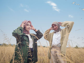 Friends standing on field against sky