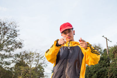 Young man looking at camera against sky