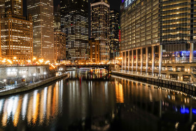 Illuminated buildings by river at night