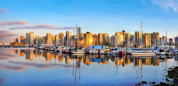 Boats moored in harbor against buildings in city