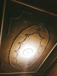 Low angle view of illuminated light bulb hanging on ceiling
