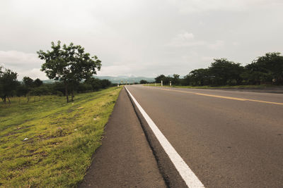 Road by trees against sky