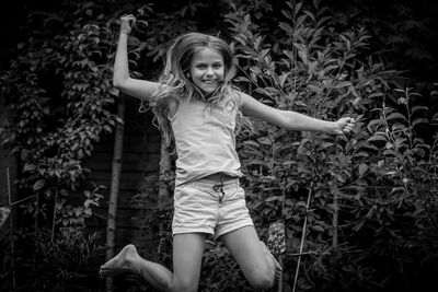 Portrait of happy girl jumping against plants