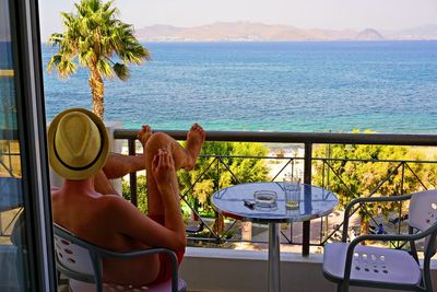 Man relaxing in balcony against sea