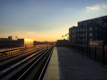 Railroad tracks amidst buildings in city against sky during sunset