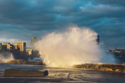 Waves splashing on sea against sky