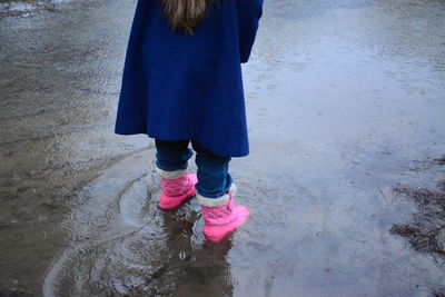 Low section of girl playing in puddle