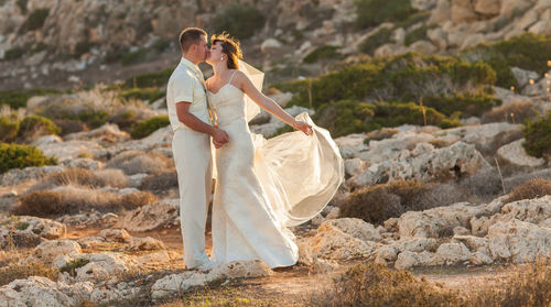 Full length of woman with arms raised on rock