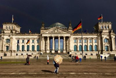 People at reichstag building against sky