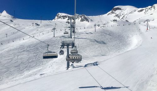 Ski lift over snowcapped mountains against sky