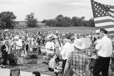 Crowd standing by tree against sky