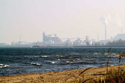 View of factory by sea against clear sky