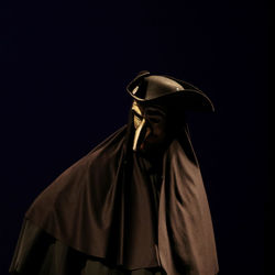 Close-up of actor wearing mask against black background