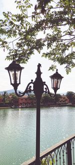 Street light by lake against sky