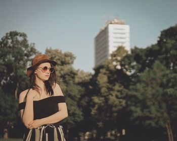 Woman wearing sunglasses standing against trees