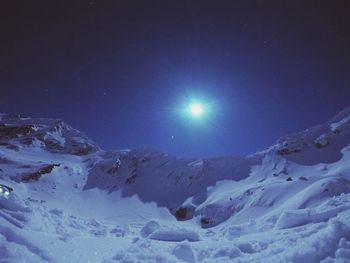 Scenic view of snow covered mountains against blue sky