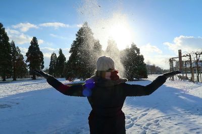 Woman standing on snow covered landscape against sky