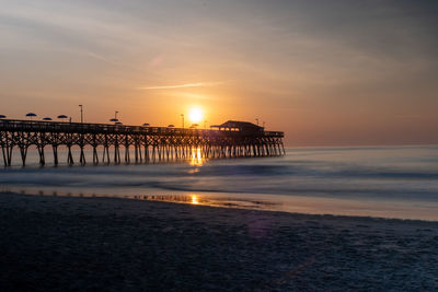 Pier over sea against sky during sunset