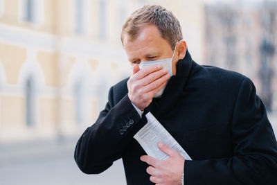 Portrait of man holding paper outdoors