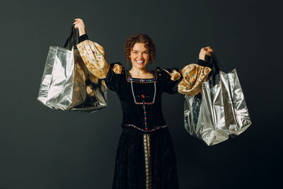 Portrait of woman standing against black background